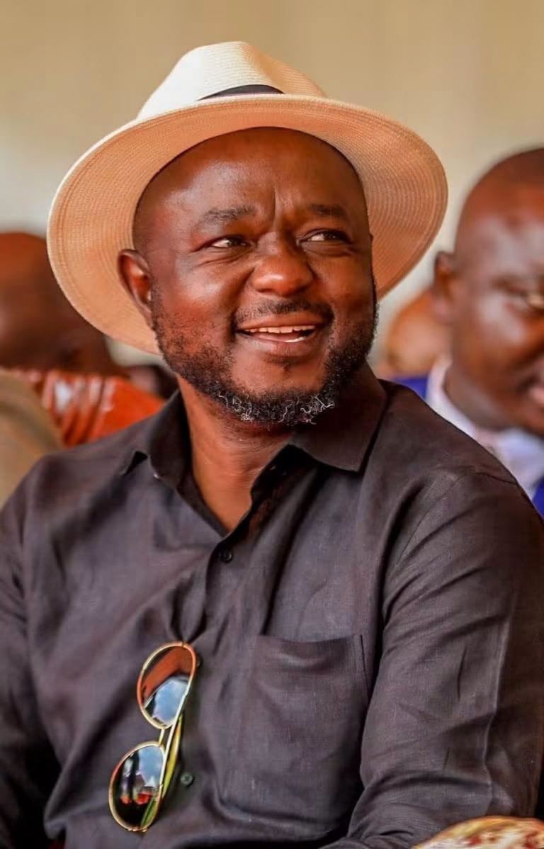 Mark Nyamita smiling, wearing a straw hat at an outdoor event