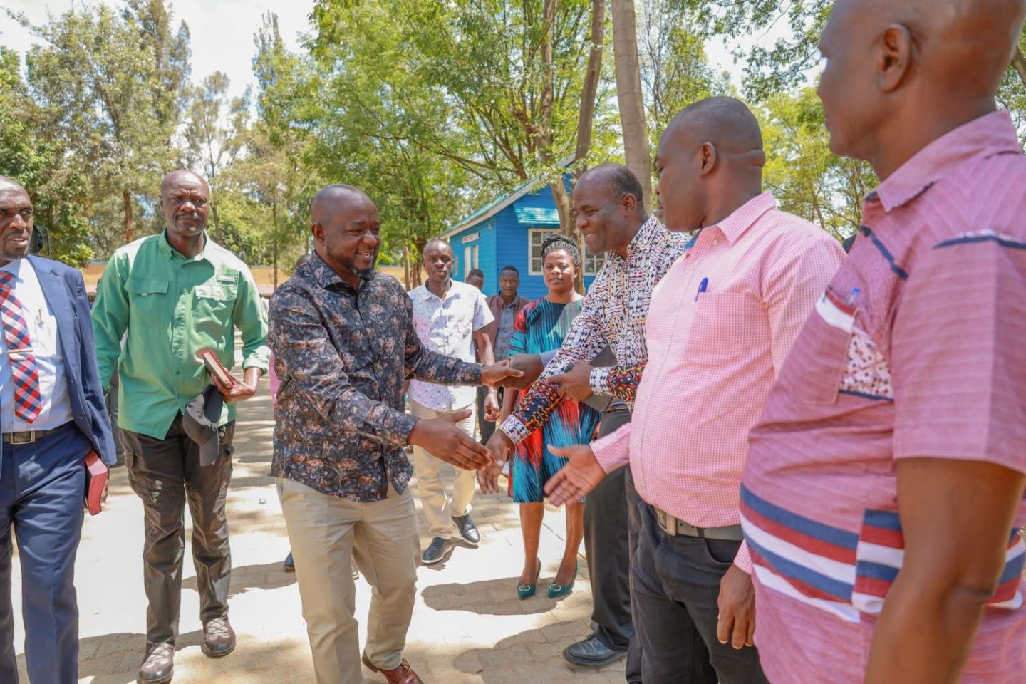 Officials greet residents along a road during a site visit