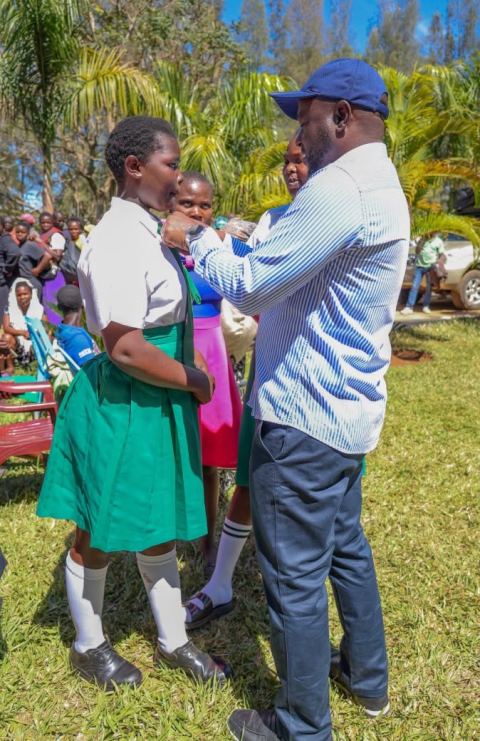 Mark Nyamita talking with a schoolgirl in uniform on a school field
