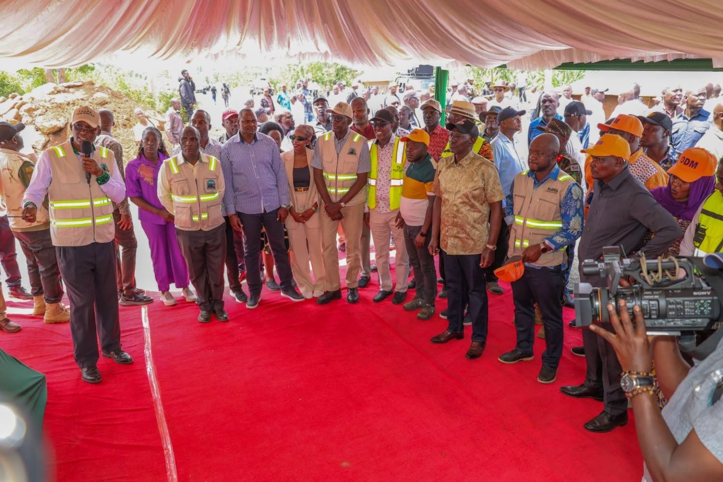 Officials and residents gathered under a tent at a community meeting